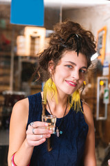 Alcohol drink. Fashionable appealing hippie woman with red lips holding alcohol drink sitting in bar