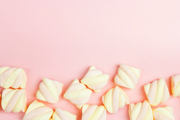 Border of  spiral marshmallows on pink background with copy space.