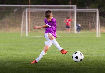 Boy kicking football on the sports field
