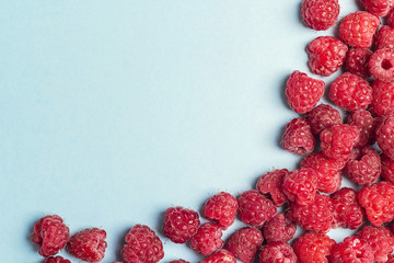 Fresh raspberries on blue background with copy space.