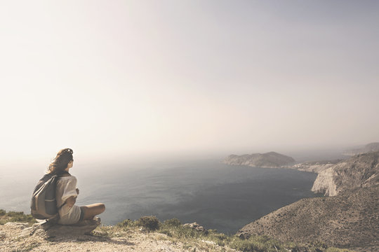 traveling woman relaxes and meditates on the peak of a mountain