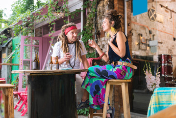 Hippies communicating. Couple of happy fashionable hippies communicating while sitting in the bar