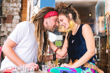 Hippie man. Laughing dark-haired woman wearing bright yellow earrings touching her hippie man