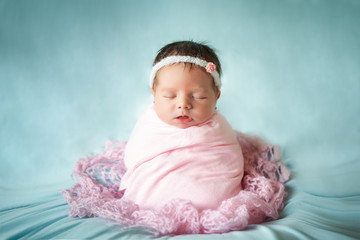 Newborn baby girl peacefully sleeping in a potato sack pose