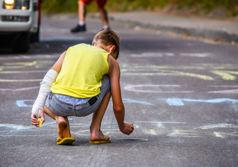 Kid drawing with chalk on the road © Dorian