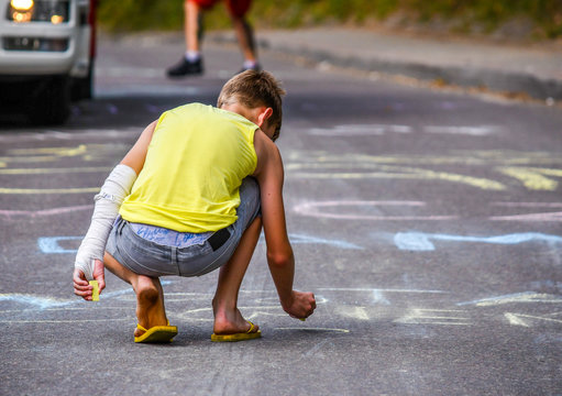 Kid drawing with chalk on the road