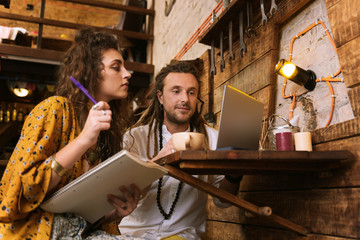 New startup. Couple of young entrepreneurs looking at their laptop while working on their new...