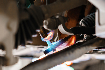 Car mechanic inspecting car wheel and repair suspension detail. Lifted automobile at repair service...