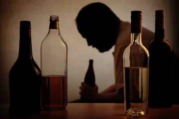 Deurstickers silhouet van een persoon die drinkt achter flessen alcohol met toegevoegd filter © Axel Bueckert