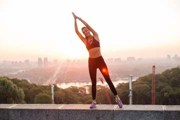 Feeling the balance. Young beautiful fit woman in sportswear doing yoga while standing against industrial city view