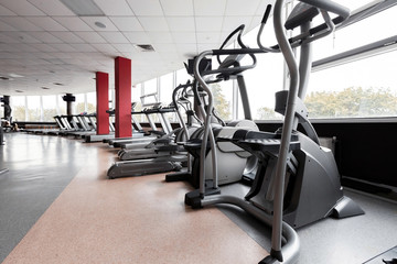 Fototapeta na wymiar Gym interior with modern equipment. light modern room with row of elliptical trainers. concept of sport and healthy lifestyle
