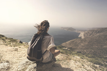 traveling woman relaxes and meditates on the top of a mountain