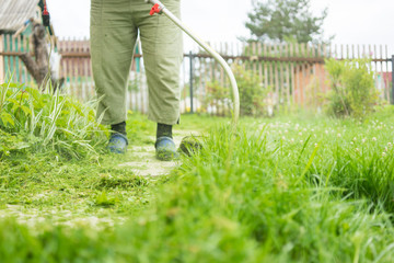 Woman mowing the grass, the mower close up