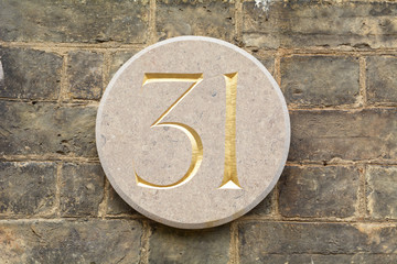 Circular house number 31 sign on wall