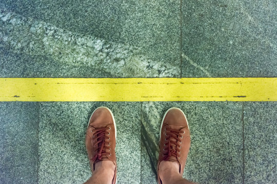 A young man stands on a platform at the warning yellow line in the subway