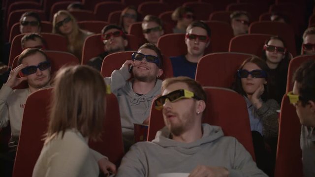 Man talking on phone in cinema hall. Uncultured man disturb people in movie theatre. Man bothering people watching 3d film in cinema. Uncultured manners at cinema