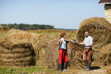 Male and female farmers looking at hay sample while working outdoors by stack © pressmaster