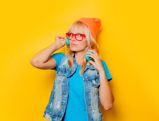 portrait of trendy adult girl orange hat with headphones on yellow background