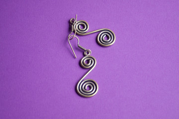 Fototapeta na wymiar silver earrings in the form of a spiral on a purple background