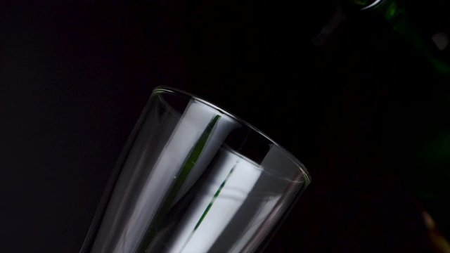 4K Slow motion draft beer pouring into the glass with bubble against dark background