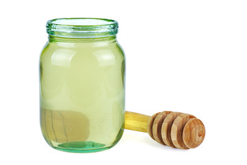 Opened glass jar with white acacia honey and wooden stick near