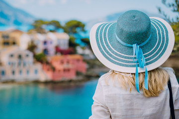 Rear view of tourist woman wear blue sunhat and white clothes admire view of colorful tranquil...