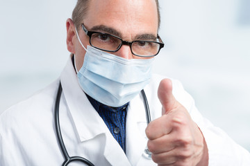 Arzt mit Mundschutz und Stethoskop zeigt Daumen hoch