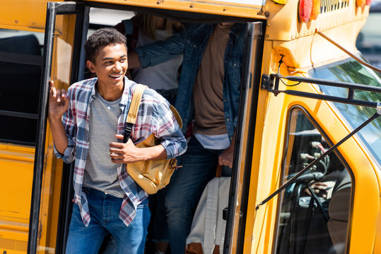 African American Happy Student Walking Out Of School Bus With Classmates