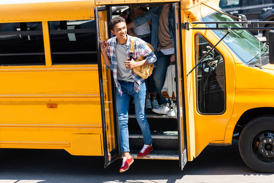 African American Teen Schoolboy Walking Out Of School Bus With Classmates