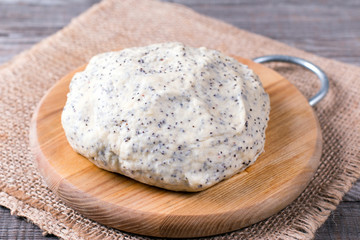 Raw dough with poppy seeds on cutting board