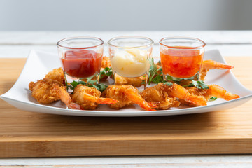 Batter-fried prawns in white plate with sauce