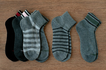 Classic socks on a wooden background. View from above. Gray and dark socks made of soft warm jersey. Clothes for the cold seasons.