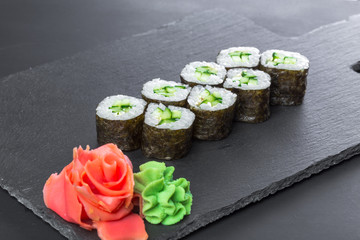Japanese restaurant, sushi roll on black slate plate.