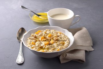 Pumpkin oatmeal with honey and nuts, milk, walnuts on a gray background. healthy delicious homemade breakfast