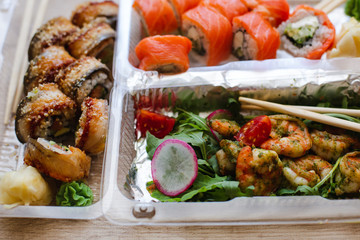 Delicious Sushi and Shrimps in Plastic to-go Boxes. Delivery of Sushi to the House. Different Types of Appetizing Sushi in Plastic Containers. Japanese Food.