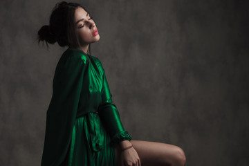 sensual woman wearing a green silk dress sitting