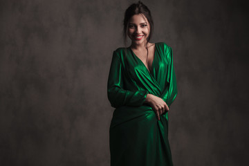 Naklejka premium smiling brunette woman covering herself with her green dress