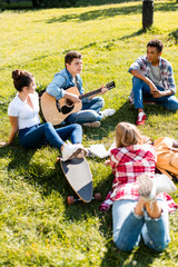 group of teenagers spending time together and listening to guitar song