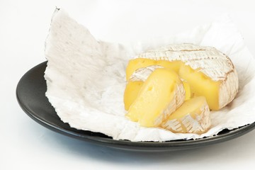A soft ripened Camembert cheese on a dark plate