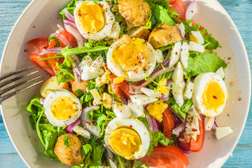 Traditional French village lunch - salad with tomatoes, arugula, potatoes and boiled eggs