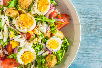 Traditional French countryside lunch - salad with tomatoes, arugula, potatoes and boiled eggs in a plate on rustic wooden table - copy space