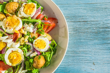 Traditional French countryside lunch - salad with tomatoes, arugula, potatoes and boiled eggs in a plate on rustic wooden table - copy space
