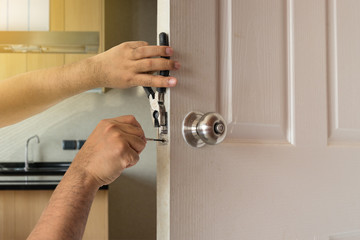 locksmith fix door by screwdriver in kitchen house - obrazy, fototapety, plakaty