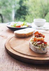 Mozzarella cheese, cherry tomatoes and arugula pesto bruschetta on light background, top view. Arugula pesto and sandwiches - tasty snack, snack, tapas
