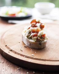 Mozzarella cheese, cherry tomatoes and arugula pesto bruschetta on light background, top view. Arugula pesto and sandwiches - tasty snack, snack, tapas