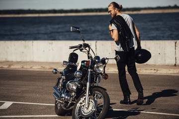 young biker with chopper motorcycle in city with river