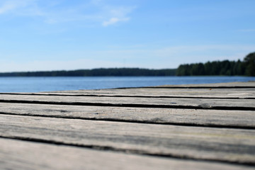 Fototapeta na wymiar Low angle view of wooden pier. Lake on background. Shallow depth of field.
