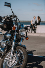 selective focus of classical chopper motorbike with couple on background