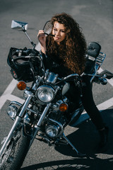 Fototapeta na wymiar curly woman sitting on chopper motorbike with helmet on urban parking