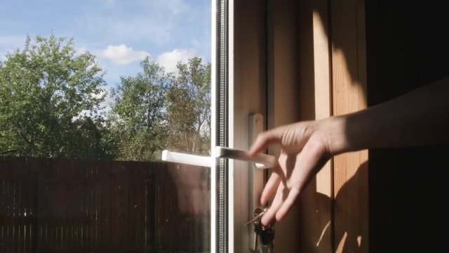 Male hand opening a glass door with a key